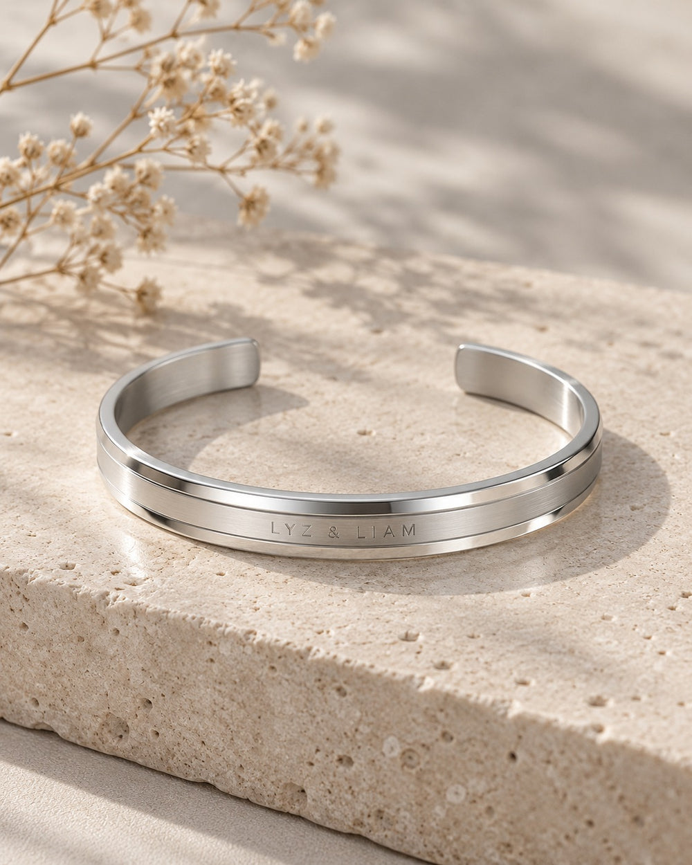 Lyz & Liam Elan Cuff Silver trên phiến đá cạnh cành hoa khô