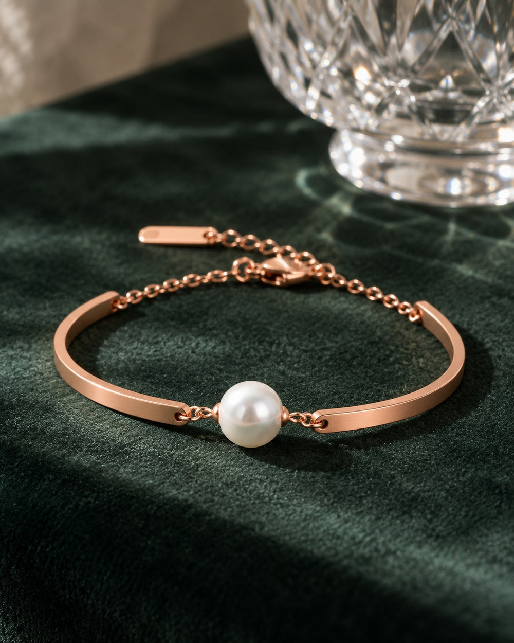 Pearl Bracelet Rose Gold trên nhung xanh cạnh ly pha lê