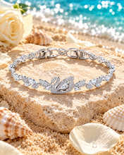 Vòng tay Crystal Dancing Swan đặt trên đá cát, vỏ sò và hoa hồng trắng