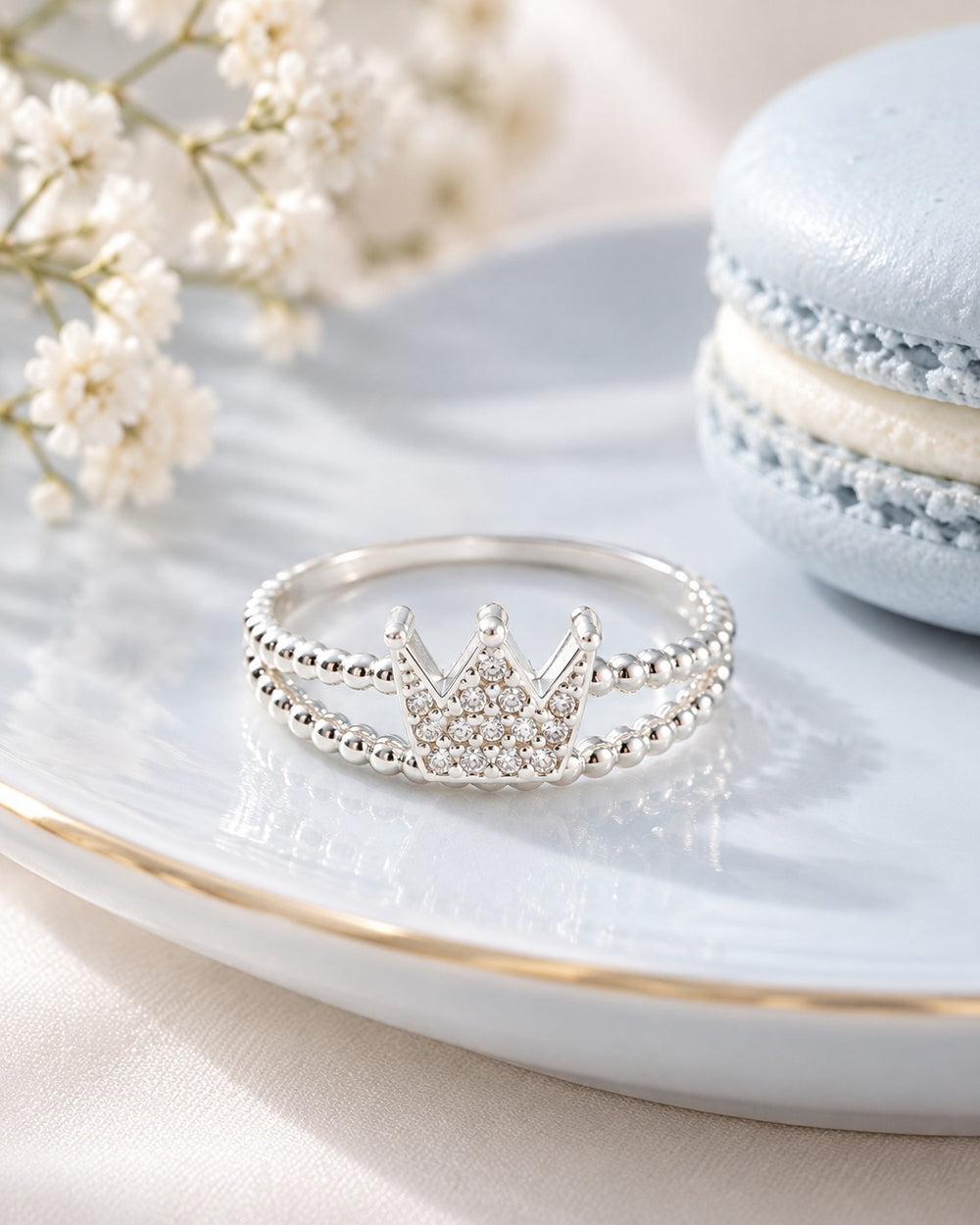 Nhẫn vương miện Unique Crown 8251SV LAMY trên đĩa sứ cạnh bánh macaron